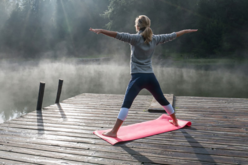 Woman in yoga pose on dock.