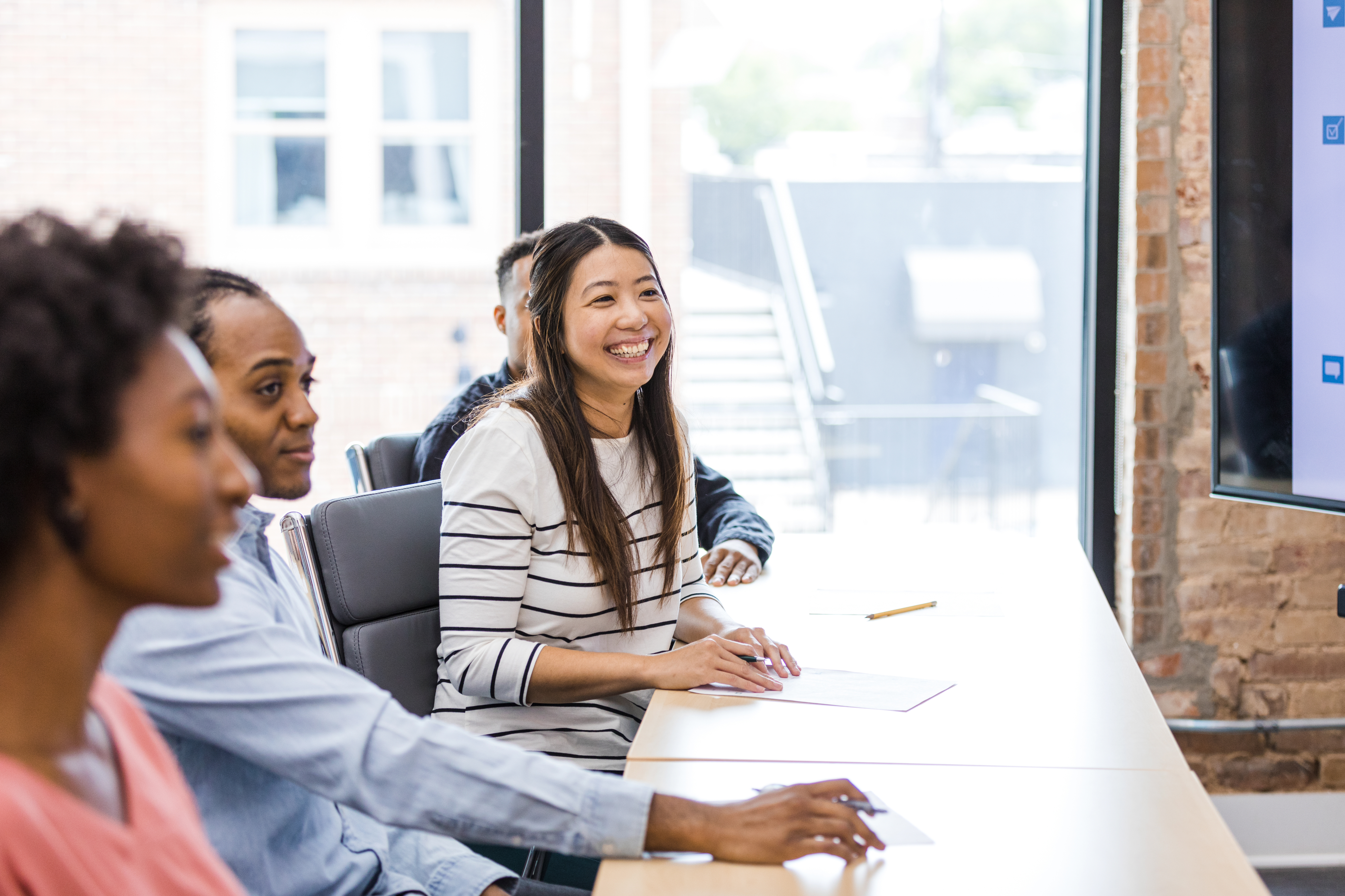 woman working at desk with colleagues in a meeting.