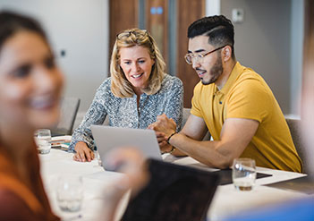 Man and woman looking at a laptop in a meeting room.